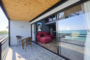 a balcony with a red couch and a table and chairs at Beachside Hotel H8 in Ban Nong Si Tong +3 photos
