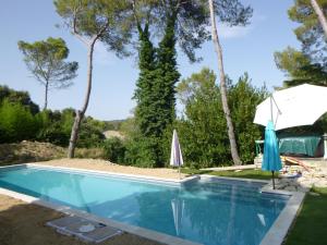 a swimming pool with an umbrella and umbrellas at Lou Mazet - Entre Vignes et Garrigue in Valflaunès