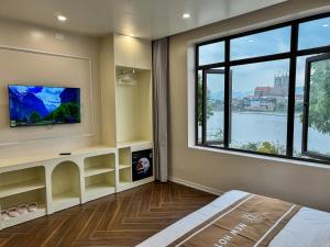 a living room with a tv and a large window at New Hotel Phủ Lý in Trượng Trâu