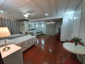 a living room with a bed and a table and a room with at Hotel Magnólia in São João da Boa Vista