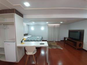 a room with a bed and a desk and a television at Hotel Magnólia in São João da Boa Vista