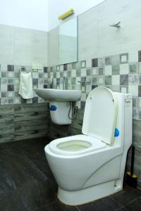 a bathroom with a white toilet and a sink at Hamilton View in Negombo