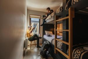 a man sitting in a chair in a room with bunk beds at Hostal Boutique Factoria Patagonia in Puerto Natales