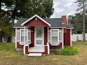 a small red house with a white door at White Mountain Cottages in North Conway