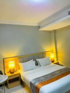 a bedroom with a large bed with two lamps at Abad Hotel in Mogadishu