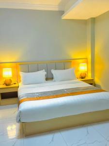 a bedroom with a large white bed with two lamps at Abad Hotel in Mogadishu