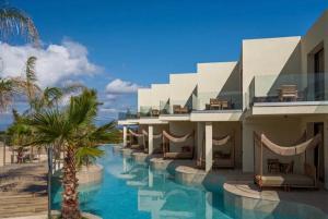 a resort with a swimming pool and palm trees at Perla Del Mare in Alikanas