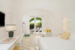 ein weißes Schlafzimmer mit einem Bett, einem Schreibtisch und einer Couch in der Unterkunft Sina Flora in Capri + 45 Fotos