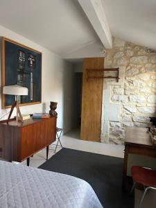 a bedroom with a bed and a desk and a stone wall at Maison Cerise in Arles