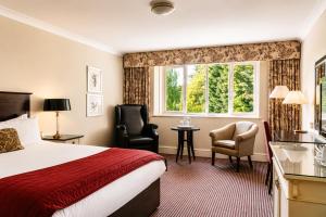 a hotel room with a bed and two chairs and a window at Macdonald Berystede Hotel & Spa in Ascot +45 photos