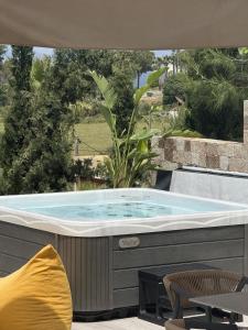 a hot tub in a patio with a table and chairs at Celeste Sea View Home with Jacuzzi and BBQ in Psalidi