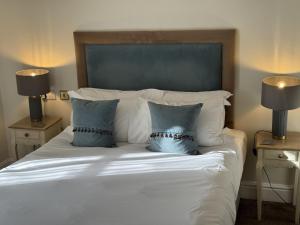 a white bed with two blue pillows on it at The Old Fourpenny Shop Hotel in Warwick