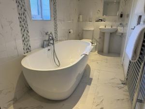 a white bathroom with a tub and a sink at The Old Fourpenny Shop Hotel in Warwick