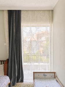 a bedroom with a large window with curtains at Pinetree House in Nafplio