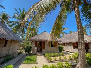 a couple of huts on the beach with palm trees at Le Renala Morondava in Morondava