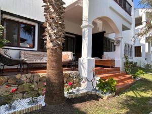 a house with a palm tree and a porch at Cabo garden in Cabo Negro