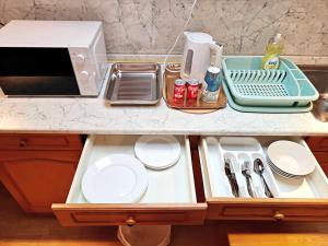 a kitchen counter with plates and a microwave at Angela Hostel in Fram