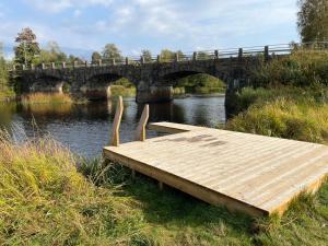 a wooden dock on the side of a river with a bridge at Visseltofta old café - unexpected and picturesque in Osby