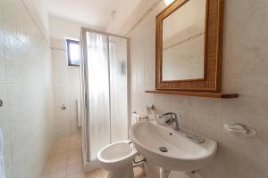 a bathroom with a sink and a toilet and a mirror at Hotel Voce del Mare in Capoliveri