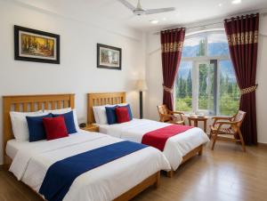 a bedroom with two beds and a table and a window at Hispar Hotel Skardu in Skardu