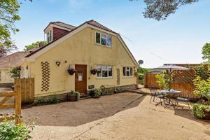 a small yellow house with a patio and a table at 2 Bed in Godshill oc-78573 in Godshill