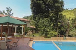 a patio with a table and an umbrella next to a pool at Hospedagem Arte na Cura in Guarapari