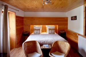 a bedroom with a bed and two wicker chairs at Auberge du Bachelard in Uvernet
