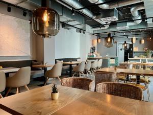 a restaurant with wooden tables and chairs and lights at HIAMO Hotel Hamburg-Bergedorf in Hamburg