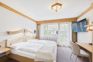 a bedroom with a bed and a desk and a window at Suite with Mountain View near Saas-Fee in Saas-Almagell