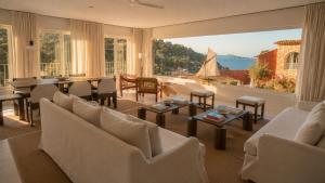 a living room with white furniture and a large window at Finca Victoria, a Member of Design Hotels in Begur