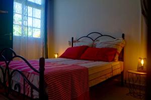 a bedroom with a bed with red pillows and a window at Cocon Kréyòl in Sainte-Anne