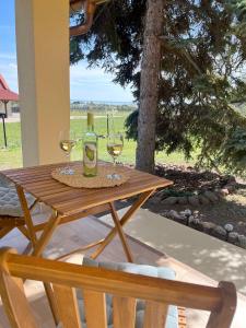 a wooden table with wine glasses and a bottle of wine at Ezüstfenyő vendégház in Balatonalmádi