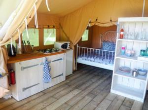a tent with a kitchen and a stove in a room at Ingerichte safaritent in Saint-Priest-en-Murat
