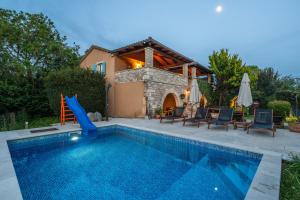 a swimming pool with a slide next to a house at Casa Karnevali in Žminj
