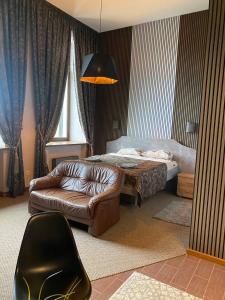 a living room with a bed and a leather chair at GRAND Restaurant&Hotel in Daugavpils