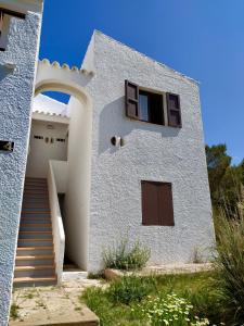 a white house with a staircase and a window at Sa Cala C16 in Cala Morell