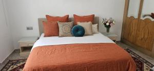 a bedroom with a large bed with orange sheets and pillows at Apartment in recent residence in Monastir
