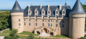 an old castle with turrets on a grass field at Le Chapitre Français 3 in Rochechouart
