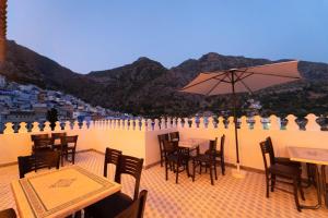 a patio with tables and chairs and an umbrella at Ahlan Riad Chefchaouen in Chefchaouen