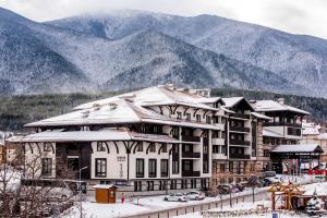 a large building in the snow with mountains in the background at Lion Bansko Hotel in Bansko