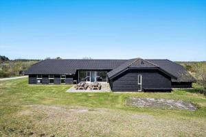 a house with a black roof on a grass field at JB500-Brovst-Kronvildtvej-31 in Tranum Strand