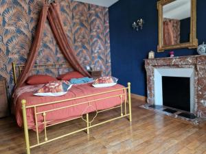 a bedroom with a canopy bed and a fireplace at Le Reflet de la Semoy in Les Hautes-Rivières