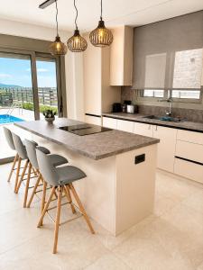 a kitchen with a large island with chairs and a counter at Elysian View Lefkakia in Nafplio