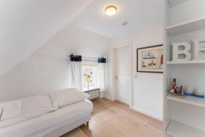 a living room with a white couch and a window at Friesenhaus Hideaway Hüs in Morsum