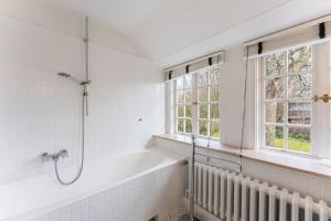 a bathroom with a bath tub and two windows at Friesenhaus Hideaway Hüs in Morsum +17 photos