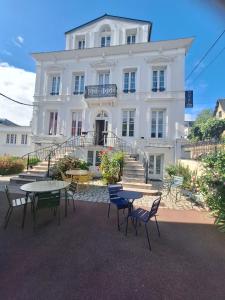 a white building with tables and chairs in front of it at Hotel de Charme La Bonne Adresse - Logis hotels in Le Havre