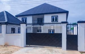 a white house with a black gate at EH Apartments in Benin City
