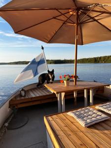 a dog sitting on a table on a boat with an umbrella at Saimaa Experience - laivamajoitus in Puumala +7 photos