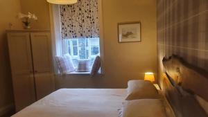 a small bedroom with a bed and a window at Neidpath inn in Peebles