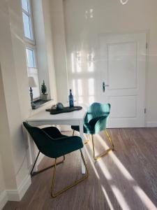 a room with a table and two green chairs at Schonekind Appartement Soest in Soest